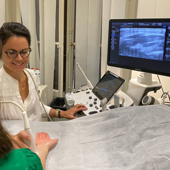 Photo d'une médecin radiologue en train de réaliser une échographie d'un poignet douloureux chez Medimage à Genève